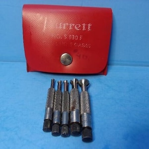 May include: A set of five silver-colored metal telescoping gages with knurled handles, arranged in a row. Behind them is a red vinyl storage pouch with a snap closure, featuring the text Starrett No. S 830 F Telescoping Gages printed in white.