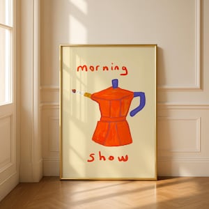Könnte beinhalten: Ein gerahmter Kunstdruck mit einer skurrilen Illustration einer roten Kaffeemaschine mit blauen und gelben Akzenten. Die Worte "morning show" sind in Rot über und unter der Kaffeemaschine geschrieben. Das Kunstwerk ist vor einem cremefarbenen Hintergrund.