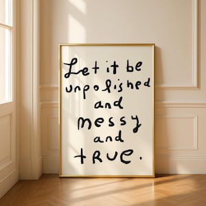May include: A framed art print with the words "Let it be unpolished and messy and TRUE" in black handwritten font. The frame is gold, and the background is a cream color.