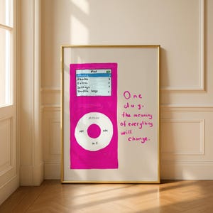 Puede incluir: Una obra de arte enmarcada con una ilustración de iPod rosa dibujada a mano. La pantalla del iPod muestra opciones de menú, y el texto "One day, the meaning of everything will change" está escrito en rosa. La obra de arte está en un marco dorado.