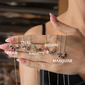 Puede incluir: Una colecci&oacute;n de collares con piedras preciosas en varias formas, incluyendo pera, ovalada, baguette, cuadrada y marquesa. Cada collar presenta gemas coloridas engarzadas en delicadas cadenas. Las etiquetas de las formas son visibles.