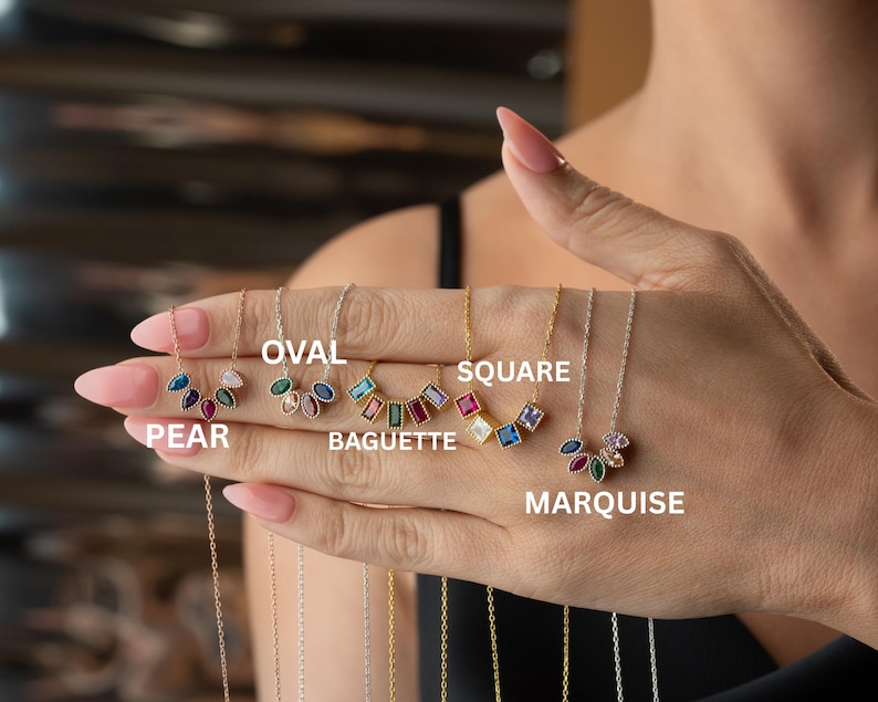 Puede incluir: Una colecci&oacute;n de collares con piedras preciosas en varias formas, incluyendo pera, ovalada, baguette, cuadrada y marquesa. Cada collar presenta gemas coloridas engarzadas en delicadas cadenas. Las etiquetas de las formas son visibles.