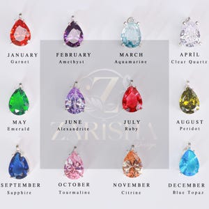 Puede incluir: Una colecci&oacute;n de doce colgantes de piedras preciosas, cada uno representando una piedra de nacimiento para cada mes. Los colgantes tienen forma de l&aacute;grima, con engastes plateados. Las piedras preciosas incluyen granate, amatista, aguamarina, cuarzo transparente, esmeralda, alejandrita, rub&iacute;, peridoto, zafiro, turmalina, citrino y topacio azul.