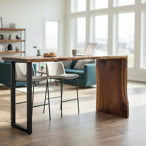 May include: A contemporary live edge wooden bar table with a black metal frame, accompanied by two grey upholstered bar stools. A laptop and a coffee cup are on the table. The room includes a teal sofa, a bookshelf, and a large window.