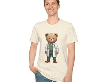 May include: Beige t-shirt featuring a cartoon bear dressed as a doctor. The bear wears a white lab coat, green scrubs, and a stethoscope. The bear is standing upright with a friendly expression. The t-shirt is made of a soft, comfortable material.