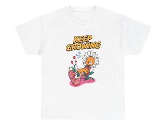 May include: White t-shirt with a cartoon daisy wearing sunglasses, relaxing in a flower pot. The daisy has a smiling face. The text "KEEP GROWING" is above the daisy in yellow and orange. The design is a fun, colourful illustration.