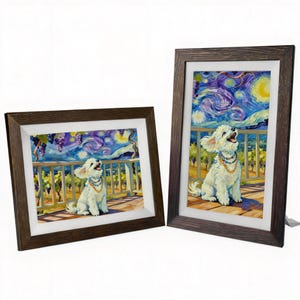 May include: Two framed art prints. Each print depicts a white dog wearing a necklace, set against a swirling night sky and vineyard. The frames are dark brown with a white border.