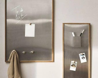 May include: Two rectangular metal memo boards with wooden frames. One board has the words "To do list" written on it, a small white paper, and a beige towel hanging below. The other board has a metal pen holder and two photos attached.