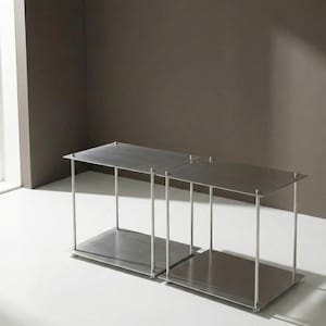 Puede incluir: Una taza de cerámica blanca con un asa negra y el texto "But First, Coffee" en negrita negra. La taza está sobre una superficie de madera. La taza mide aproximadamente 10 cm de alto.