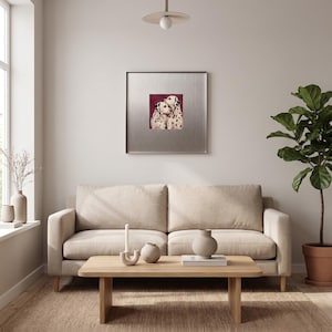 May include: A square framed wall art piece featuring two Dalmatian dogs against a deep red background, displayed above a beige sofa, a light wood coffee table with a candle and vase, and a potted plant in a bright, neutral-toned room.