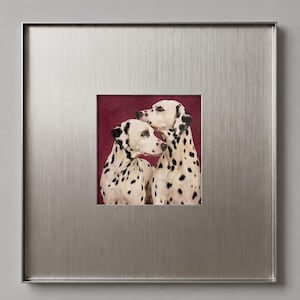 May include: A square wall art piece featuring a portrait of two Dalmatian dogs with white coats and black spots. The dogs are positioned against a deep burgundy background. The artwork is encased in a wide, brushed silver metal frame.