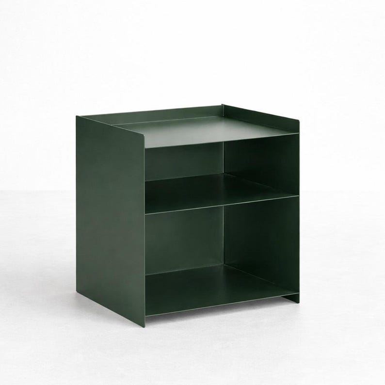Puede incluir: Una unidad de almacenamiento de metal en color verde bosque oscuro con un dise&ntilde;o cuadrado de frente abierto y dos estantes horizontales. La estructura est&aacute; compuesta por paneles s&oacute;lidos y lisos con un borde elevado en la superficie superior.