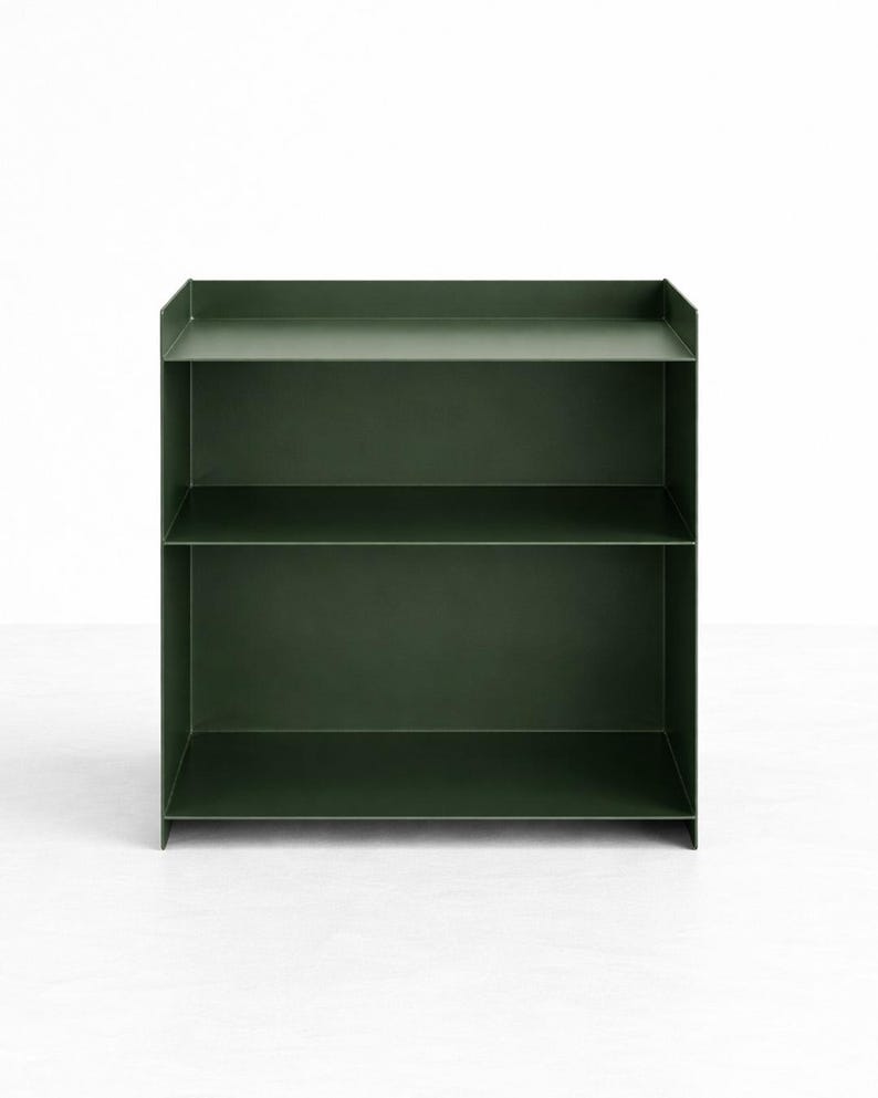 Puede incluir: Una estanter&iacute;a de metal en color verde bosque oscuro con dos niveles de almacenamiento abiertos y un borde trasero elevado en el estante superior. La estructura se compone de paneles planos y finos con l&iacute;neas rectas y un acabado mate liso.