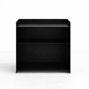 Puede incluir: Una estanter&iacute;a de metal negro mate con dos niveles de almacenamiento abiertos y una superficie superior con bordes laterales elevados. La estructura est&aacute; compuesta por paneles finos y planos con un marco rectangular y un acabado oscuro uniforme.