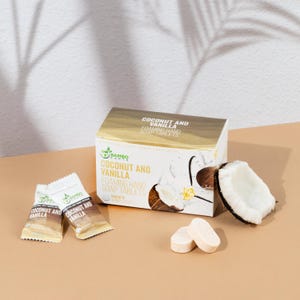 May include: A box of Coconut and Vanilla foaming hand soap tablets with two individual packets and two tablets. A coconut half is next to the box. The box has the words "Coconut and Vanilla" and "Foaming Hand Soap Tablets".