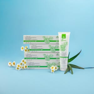 May include: A white tube of toothpaste with green detailing and text, alongside a stack of toothpaste boxes. The boxes and tube display the words "Natural Nano-Hydroxyapatite Toothpaste Aloe Vera & Chamomile". Chamomile flowers and aloe vera leaves are also visible.