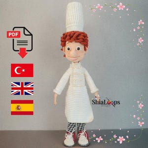 Könnte beinhalten: Handgemachte Häkelpuppe eines Kochs, der eine weiße Uniform und eine Kochmütze trägt. Die Puppe hat rotes Haar, ein lächelndes Gesicht und trägt eine schwarz-weiß karierte Hose und rote Schuhe. Die Puppe ist etwa 30 cm groß.