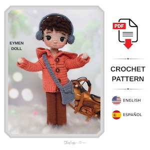 May include: A crochet doll named Eymen Doll wearing a hooded orange jacket with four buttons, brown trousers, and a gray crossbody bag. The doll has dark brown hair and wears gray headphones. The image includes text for a PDF crochet pattern.