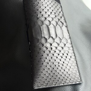Pu&ograve; includere: Un portafoglio nero rettangolare con un motivo squamoso strutturato. Il portafoglio sembra essere in pelle e ha una chiusura a patta. Il design generale &egrave; elegante e moderno, adatto per trasportare carte e contanti.
