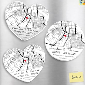 May include: Three white magnets with map designs. Two are heart-shaped, and one is round. Each features a map, a red heart, and the text "Amelia & Thomas WHERE IT ALL BEGAN M&T Bank Stadium - Baltimore, MD April 25, 2022."