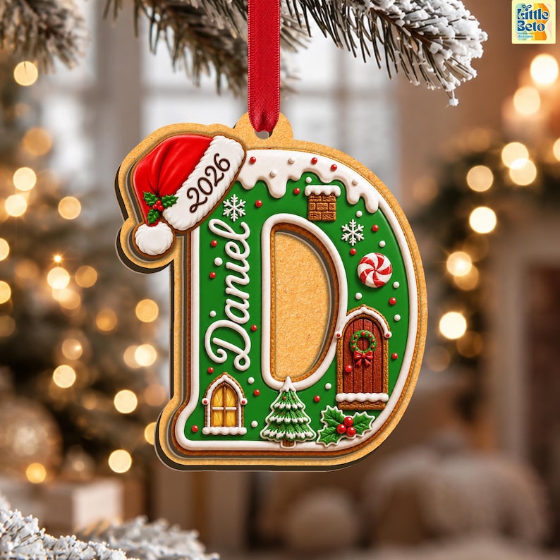 May include: A gingerbread-style letter D Christmas ornament featuring the name Daniel and the year 2026. The ornament is decorated with a red Santa hat, white icing, a brown door, a window, a green Christmas tree, and red holly berries.