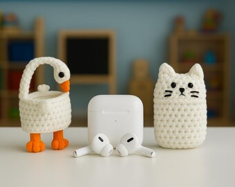 May include: A white crochet goose and cat case, along with a white charging case and earbuds. The goose has orange feet and beak, and the cat has black eyes and whiskers. The items are on a white surface.