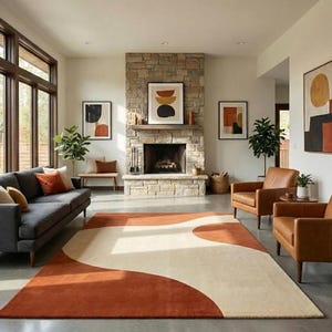 Peut inclure: Un salon moderne avec un grand tapis de couleur rouille et un motif de vagues ivoire. La pièce comprend un canapé gris, des fauteuils en cuir, une cheminée en pierre et des œuvres d'art abstraites. De grandes fenêtres laissent entrer la lumière naturelle.