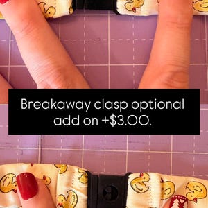 May include: A fabric strap featuring a repeating pattern of yellow ducks on a cream background, equipped with a black plastic breakaway clasp. The text Breakaway clasp optional add on +$3.00 is displayed across the centre of the image.