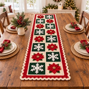 Pode incluir: Um caminho de mesa retangular de crochê com quadrados alternados em verde escuro com flocos de neve brancos e creme com flores de poinsétia vermelhas. O caminho tem uma borda creme recortada sobre uma mesa de madeira.