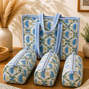 Könnte beinhalten: Ein Set aus passenden Taschen und Beuteln mit floralem Druck. Die Tragetasche und die Beutel haben einen weißen Hintergrund mit blauen und grünen Blumenmustern. Die Taschen haben blaue Streifen und Reißverschlüsse.