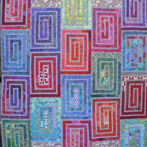 May include: A colorful quilt with a repeating pattern of squares within squares. The squares are made of different fabrics with various colors and patterns, including red, blue, green, and purple.