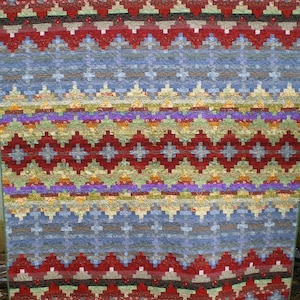 Puede incluir: Una colcha colorida con un patrón geométrico en tonos de rojo, azul, verde y amarillo. La colcha está hecha de tela de patchwork y tiene un diseño tradicional.