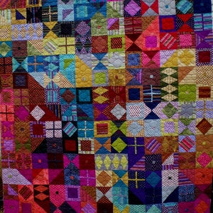 Puede incluir: Una colcha colorida hecha de varias telas con diferentes patrones y colores. La colcha está hecha de cuadrados y triángulos, y los colores incluyen rojo, naranja, amarillo, verde, azul, morado, rosa y marrón.