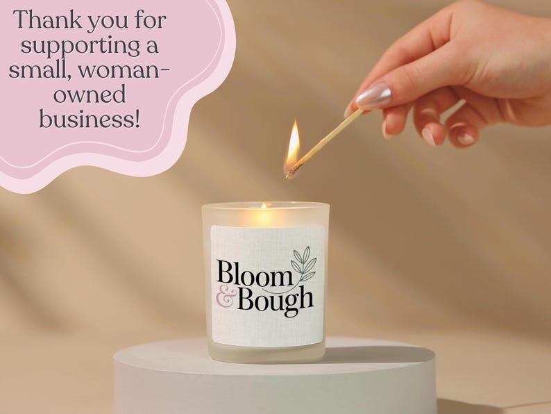 Puede incluir: Una vela encendida en un tarro de vidrio esmerilado con el texto "Bloom & Bough" en una etiqueta blanca. Se est&aacute; usando una cerilla para encender la vela. La imagen incluye el texto "&iexcl;Gracias por apoyar a una peque&ntilde;a empresa propiedad de mujeres!"