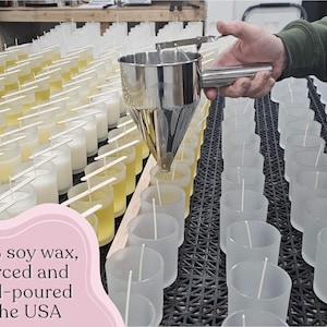 Puede incluir: Una persona vierte cera en candelabros de vidrio transparente con mechas. La imagen muestra filas de velas en varias etapas de finalizaci&oacute;n. El texto de la imagen dice: "100% cera de soja, obtenida y vertida a mano en los EE. UU."