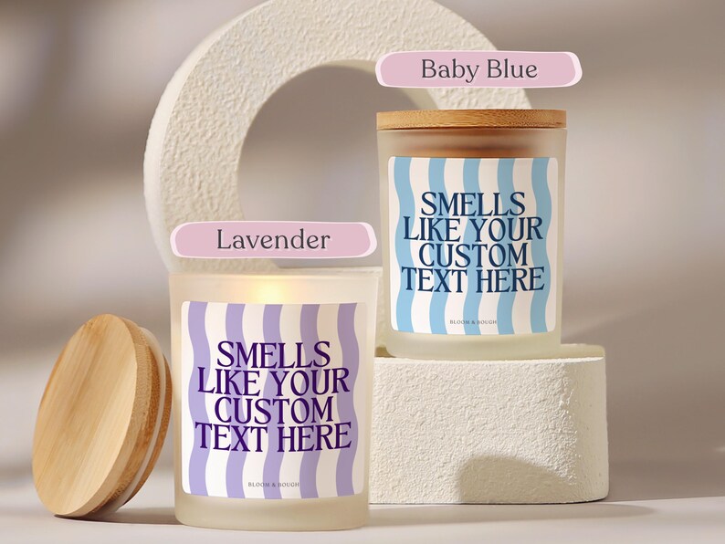 Puede incluir: Dos velas de vidrio esmerilado con tapas de madera. Una vela est&aacute; etiquetada como "Baby Blue" y la otra como "Lavender". Ambas velas tienen etiquetas con el texto "Smells Like Your Custom Text Here" en un patr&oacute;n ondulado.