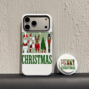 Puede incluir: Funda de teléfono blanca con un diseño verde de "MERRY CHRISTMAS". El diseño incluye a Papá Noel, un reno, un árbol de Navidad y un cascanueces. También hay un pop socket a juego.