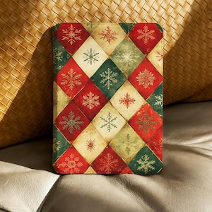 Op de afbeelding: Een rechthoekig object met een herhalend ruitpatroon in rood, groen en crème. Elke ruit bevat een sneeuwvlokillustratie. Het object heeft een vintage uitstraling met een kerstthema.