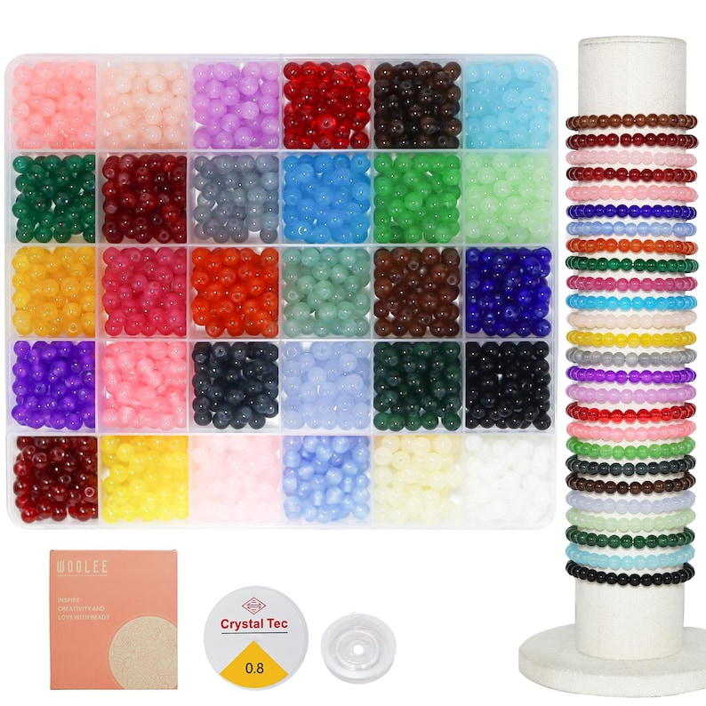 May include: A bead kit with a variety of colorful beads in a clear divided container. The beads are arranged by color, including pink, purple, red, black, blue, green, yellow, and orange. Several beaded bracelets are displayed on a white stand, along with string and other crafting supplies.