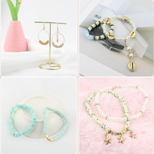 May include: A collection of jewelry including gold hoop earrings with beaded accents, beaded bracelets in blue and white, and necklaces with pearls and star charms. The jewelry is displayed on a white surface and a pink surface.