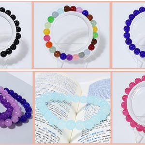 May include: A collection of beaded bracelets in various colors, including black, rainbow, blue, purple, and pink. The bracelets are displayed on clear stands, showcasing the round beads. Some bracelets are stacked together.