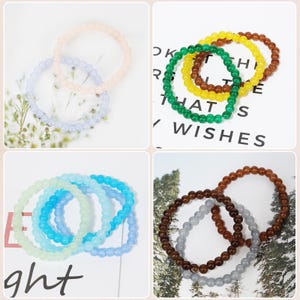 May include: A collection of beaded bracelets in various colors, including pink, lavender, light blue, green, yellow, brown, and gray. The bracelets are made of small, round beads and are arranged in sets of two or three.