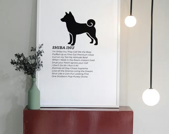 Puede incluir: Impresión enmarcada en blanco con una silueta negra de Shiba Inu y texto humorístico. La impresión está sobre una estantería burdeos con un jarrón verde y ramitas decorativas. Una moderna lámpara negra con dos luces de globo blancas cuelga detrás.