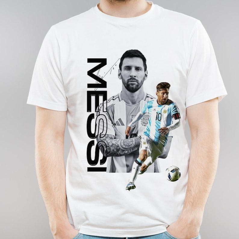 May include: White t-shirt featuring a graphic of Lionel Messi in action, with the name "MESSI" printed vertically in black. The design includes two images of Messi, one in a jersey and another in a portrait style.