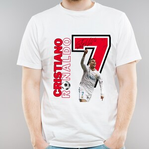 May include: White t-shirt featuring a graphic of Cristiano Ronaldo with the number 7 in a black and red design. The text "Cristiano Ronaldo" is printed vertically in red with a soccer ball graphic.
