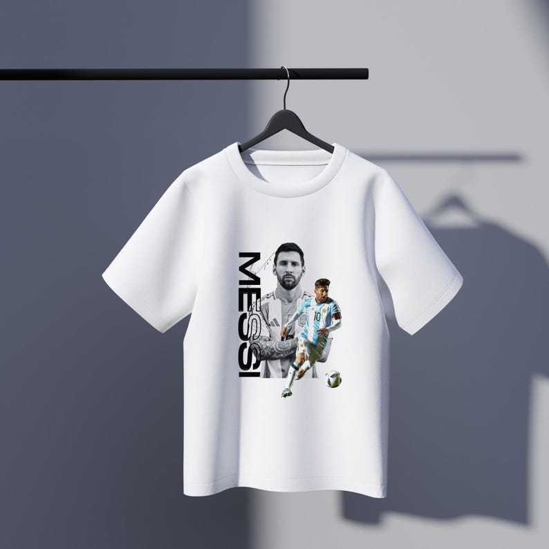 May include: White t-shirt featuring a black and white image of a soccer player, with the name "MESSI" printed vertically on the left side. The design includes two images of the player in action, one in a black and white portrait and the other in color.
