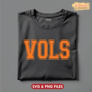 May include: A folded charcoal gray t-shirt with the word "VOLS" in orange block letters. The text has a thin orange outline. The bottom of the image has the text "SVG & PNG FILES" in a red rectangle.