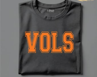 Könnte beinhalten: Ein gefaltetes, anthrazitfarbenes T-Shirt mit dem Wort "VOLS" in orangefarbenen Blockbuchstaben. Der Text hat eine dünne orangefarbene Umrandung. Am unteren Bildrand steht "SVG & PNG FILES" in einem roten Rechteck.