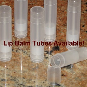 May include: A group of eight clear plastic lip balm tubes. The tubes are empty and ready to be filled with lip balm. The text "Lip Balm Tubes Available!" is printed on the table surface.