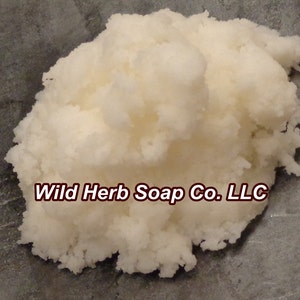 May include: A close-up of a white, fluffy, soap base. The soap base is on a gray surface. The text "Wild Herb Soap Co. LLC" is visible in the image.